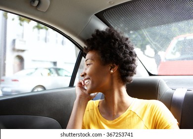 Close up portrait of happy young african woman sitting in car talking on cellphone 