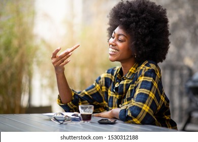 Close up portrait of happy young black woman holding and looking at a cookie