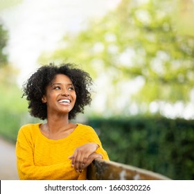 Close Up Portrait Of Happy Young Black Woman Relaxing On Bench Outside 