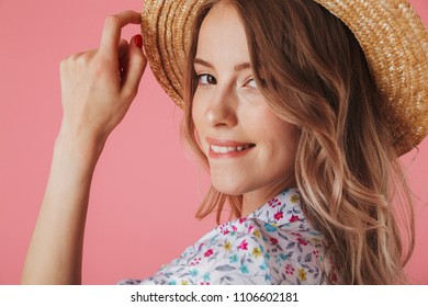 Close up portrait of a happy young woman in summer dress and straw hat posing and looking at camera isolated over pink background - Shutterstock ID 1106602181