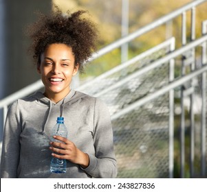Close up portrait of a happy young woman smiling with water bottle