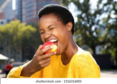 Close Up Portrait Of Healthy Young Black Woman Eating Apple Outdoors