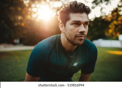 Close Up Portrait Of Healthy Young Man Standing Outdoors In Park And Looking Away. Confident Young Man Ready Of Workout.