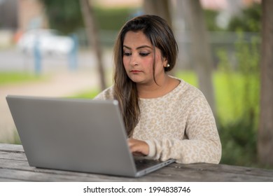 Close Up Portrait Of Indian Woman Working On Laptop Computer Outdoor. South Asian Indian Woman Sitting With Computer On Table.