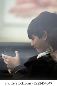 Close Up Portrait Of Kids With School Uniform Through The Car Window Glass Playing With Smartphone. Side View