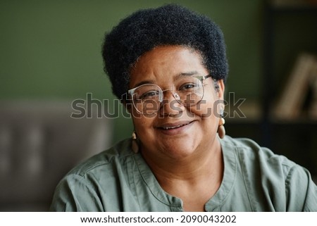 Close up portrait of kind black senior woman smiling at camera at home, copy space