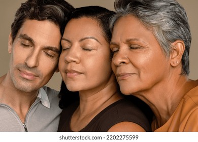 Close up portrait of a Latino man in his 40's, a Hispanic woman in her 60's, and an Afro-Latina woman in her 40's with their eyes closed on a neutral background. - Powered by Shutterstock