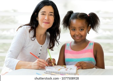 Close Up Portrait Of Little African Girl And Caucasian Teacher At Home. Kid Having Private Art Drawing After School Lesson.