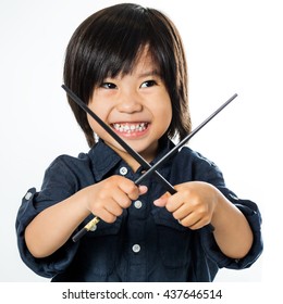 Close up portrait of little asian boy playing with chopsticks.Isolated on white background.
