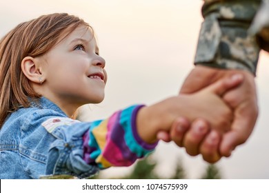 Close up portrait little girl looks at his military father. Lovely gaze of a daughter, holding hands.