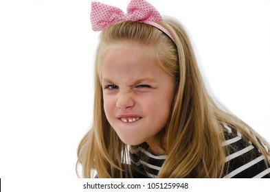 Close Up Of A Portrait Little Girl Shows Her Furrowed Brow And Irritated Frown. Isolated On White Background