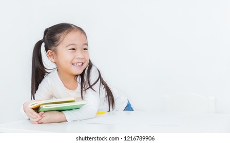 Close Up Portrait Of Little Happy Cute Asian Toddler Girl Sitting Reading A Book Isolated On White Background. Home School Education Study Grade Student Back To School Concept