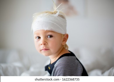 Close Portrait Of Little Toddler Boy With Head Injury, Sitting In Bed, Tired, Looking At Camera