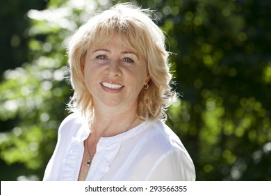 Close up portrait of lovely middle aged woman in the summer park 