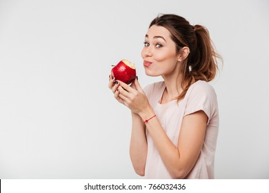Close up portrait of a lovely pretty girl biting an apple isolated over white background