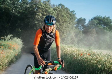 Close Up Portrait Of Male Cyclist In Professional Outfit During Training Ride On Gravel. Image Of Strong Attractive Athlete During Cycling Activity On The Road At Forest. Image Of Sportsman 