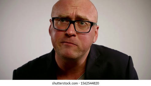 Close Up Portrait Of A Man In Glasses And Suit Chewing Food With A Disgruntled Expression