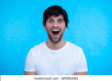 Close Up Portrait Of Man, Guy Is Shocked, Extremely Happy, With Wide Open Eyes And Mouth On Blue Background