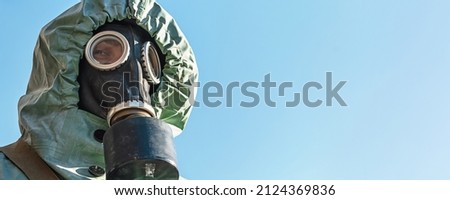 Close up portrait of man wearing respirator and protective costume standing against clear blue sky