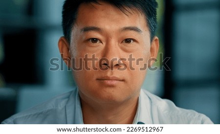 Close up portrait mature Asian man 40s businessman boss employer lawyer leader middle-aged senior Chinese Japanese Korean male posing in modern office looking at camera serious unhappy face expression