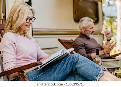 Close up portrait of mature blonde woman wearing glasses while reading near her husband and their trailer - Powered by Shutterstock