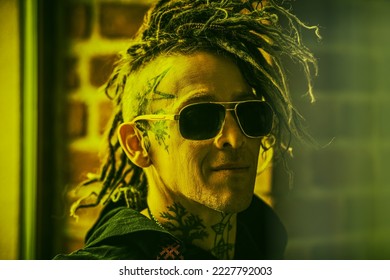 Close up portrait of a mature brutal man with ethnic tattoos on his head and neck and with punk-style Mohawk dreadlocks. Punk and rock culture. 