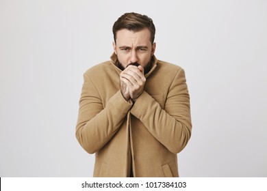 Close up portrait of mature male who feels very cold outside over white background. Man hopes that he will not get cold. Who knew that this day is bad for a date outside.