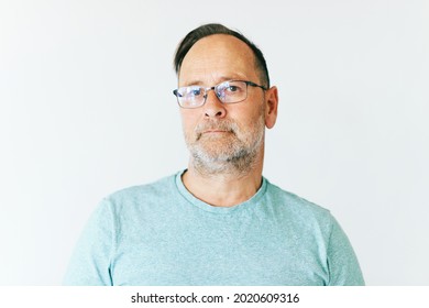 Close up portrait of middle age man wearing glasses and turquoise t-shirt, white background