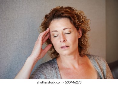 Close Up Portrait Of Middle Aged Woman With Hand To Head In Pain