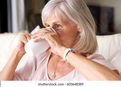 Close Up Portrait Of Older Woman Drinking Tea On Couch Indoors