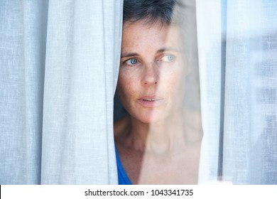 Close Up Portrait Of Older Woman Looking Opening Curtains And Looking Through Window