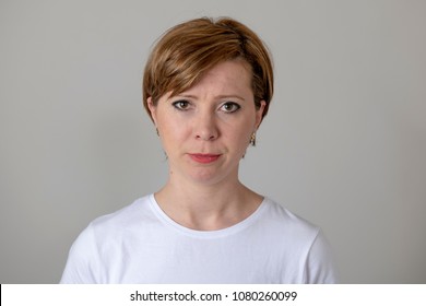 Close Up Portrait Os A Beautiful Young Red Haired Caucasian Woman With A Serious Face. Beautiful Eyes Looking Straight At The Camera. Human Facial Expressions And Emotions. Gray Background