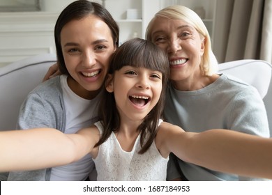 Close up portrait of overjoyed three generations of women have fun at home make selfie together, smiling little girl with young mom and senior grandmother take self-portrait picture on camera - Powered by Shutterstock