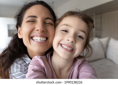 Close up portrait of overjoyed young Latino mother and little biracial daughter make selfie together. Happy Hispanic mom and small ethic girl child take self-portrait picture on camera at home. - Powered by Shutterstock