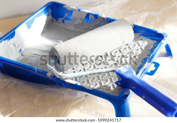 Close up portrait of paint roller in paint tray with\
color in the tray
