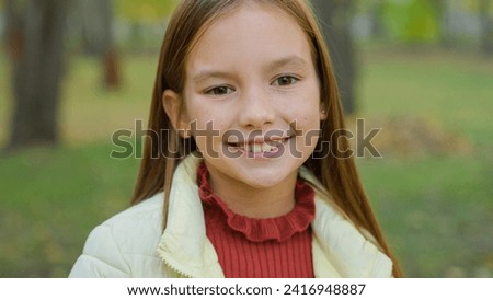 Close up portrait in park autumn alone one beautiful adorable adopted cute teen schoolgirl smiling happy positive Caucasian little girl daughter smile satisfied outdoors child kid looking at camera