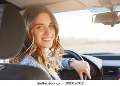 Close Up Portrait Of Pleasant Looking Female With Glad Positive Expression, Being Satisfied With Unforgettable Journey By Car, Sits On Driver`s Seat, Enjoys Music. People, Driving, Transport Concept