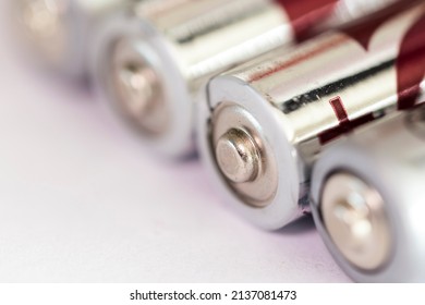 A Close Up Portrait Of The Positive Or Plus Side Of A Couple Of Triple A Or AAA Batteries Lying On An Almost White Surface.