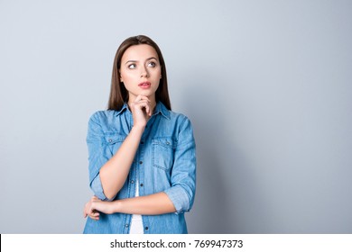 Close up portrait of pretty confident thoughtful girl, holding hand near the face, looking seriously up, standing over grey background with copy space