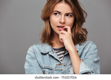 Close up portrait of a pretty pensive teenage girl in denim jacket looking away isolated over gray background - Shutterstock ID 751017016