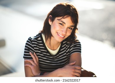 Close Up Portrait Of Pretty Young Female Sitting Outside In The City Looking At Camera And Smiling