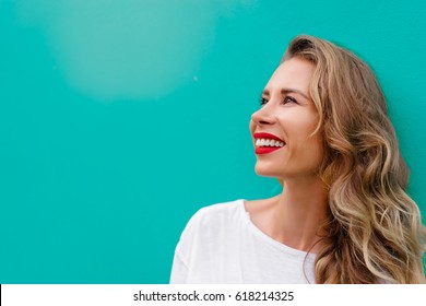 Close Up Portrait Of Pretty Young Happy Woman With Red Lips Make-up Against Green Wall.