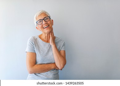 Close up portrait of a professional business woman smiling. Portrait of cheerful mature woman standing against grey wall. Close up portrait of beautiful older woman smiling and standing by wall