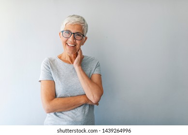 Close Up Portrait Of A Professional Business Woman Smiling. Portrait Of Cheerful Mature Woman Standing Against Grey Wall. Close Up Portrait Of Beautiful Older Woman Smiling And Standing By Wall