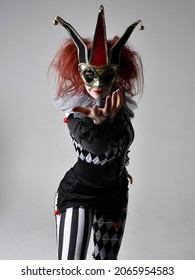 close up portrait of red haired  girl wearing a black and white clown jester costume, theatrical circus character.  Standing pose  isolated on  studio background.