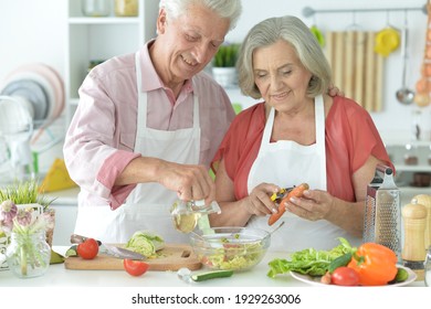 Close up portrait of senior couple making salad together at kitchen