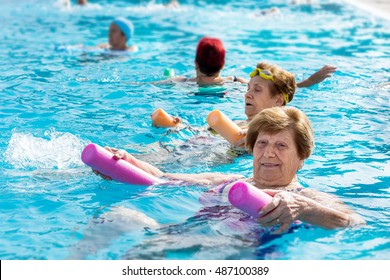 Close Up Portrait Of Senior Woman Doing Body Exercise With Friends At Aqua Gym Session In Outdoor Pool.