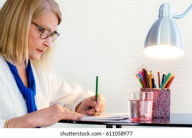 Close Up Portrait Of Senior Woman Doing Art Therapy With Coloring Book For Adults At Home.