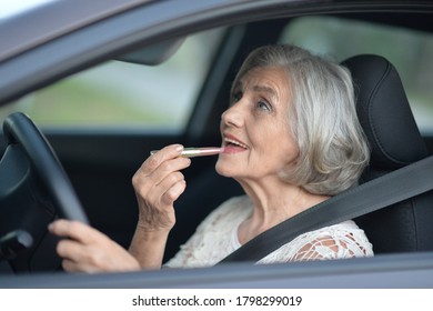Close up portrait of senior woman putting lipstick in the car