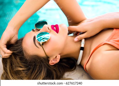 Close Up Portrait Of Sensual Glamour Model Getting Sunbathe Near Private Pool, Mirrored Sunglasses, Stylish Jewelry, Tanned Skin, Bright Make Up. Luxury Vacation Concept.